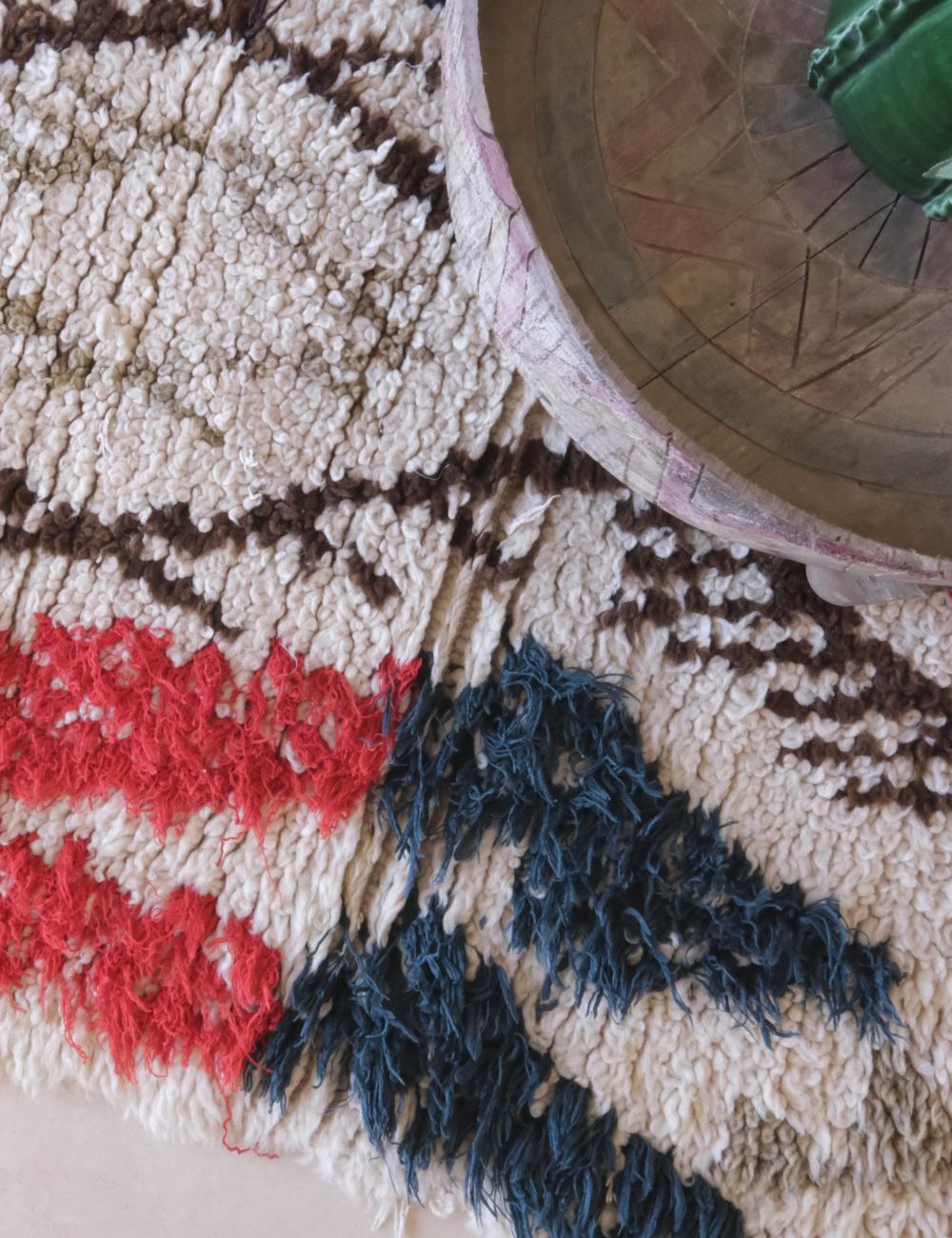 Close-up of a textured rug with geometric pattern and a wooden object on top.