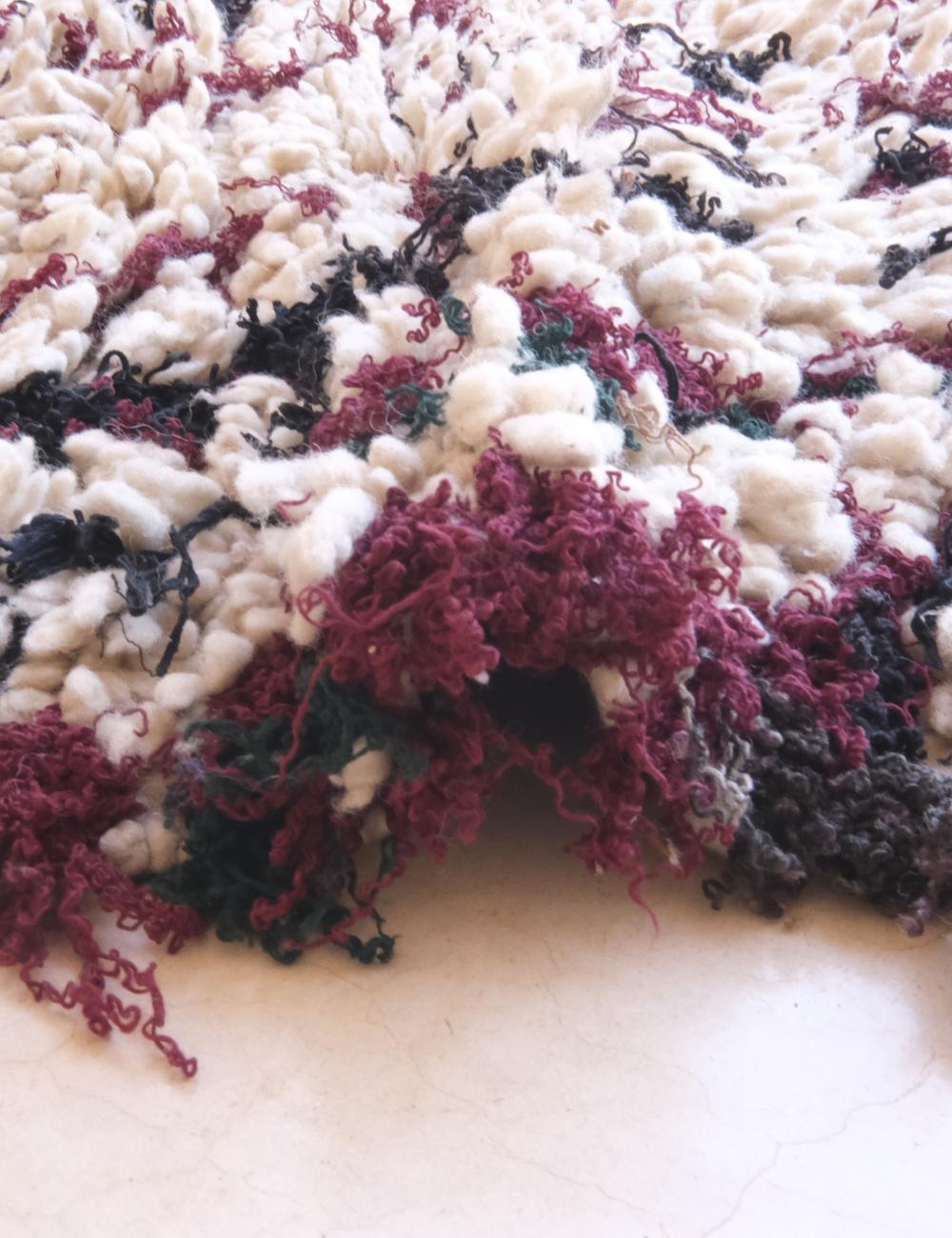 Close-up of a textured fabric with purple and black patterns on a white background