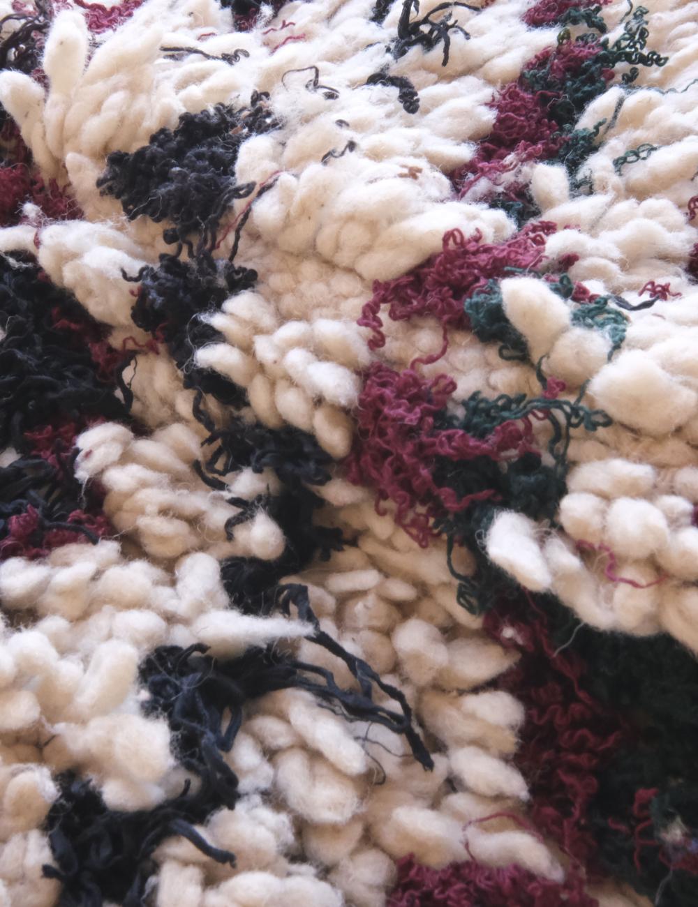 Close-up of textured fabric with black, red, and green yarn.