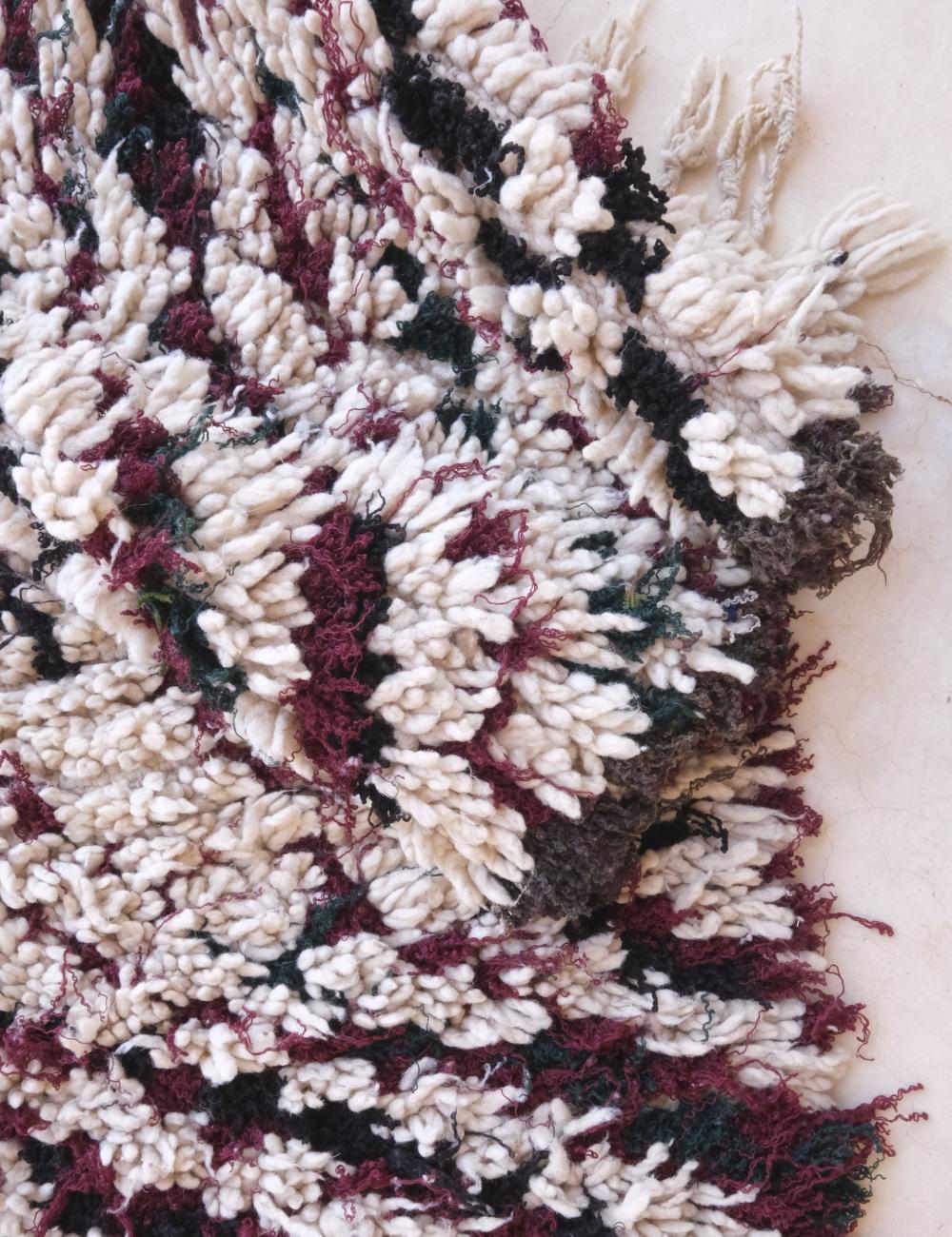 Close-up of a textured rug with a pattern of white, red, and black.