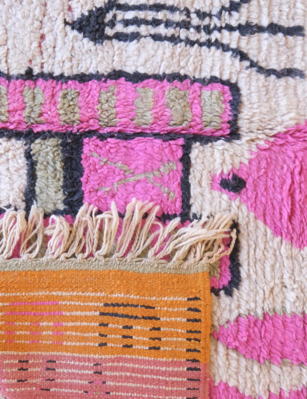 Close-up of a colorful woven textile with pink, orange, and black patterns.