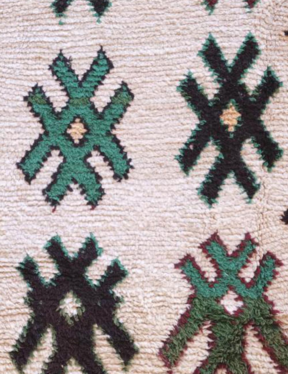 Close-up of a patterned fabric with green and black designs on a beige background