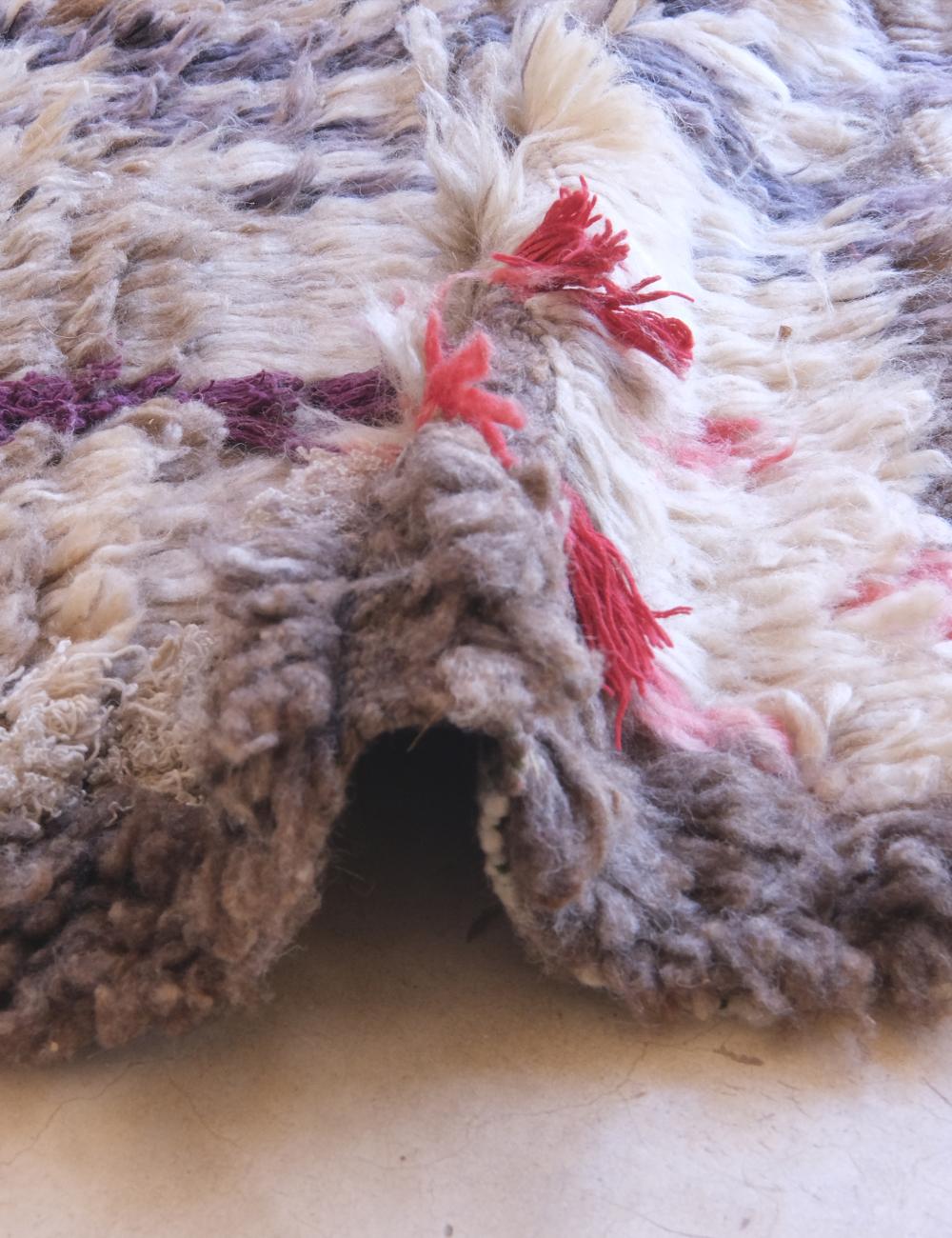 Close-up of a textured rug with colorful tassels on a light background
