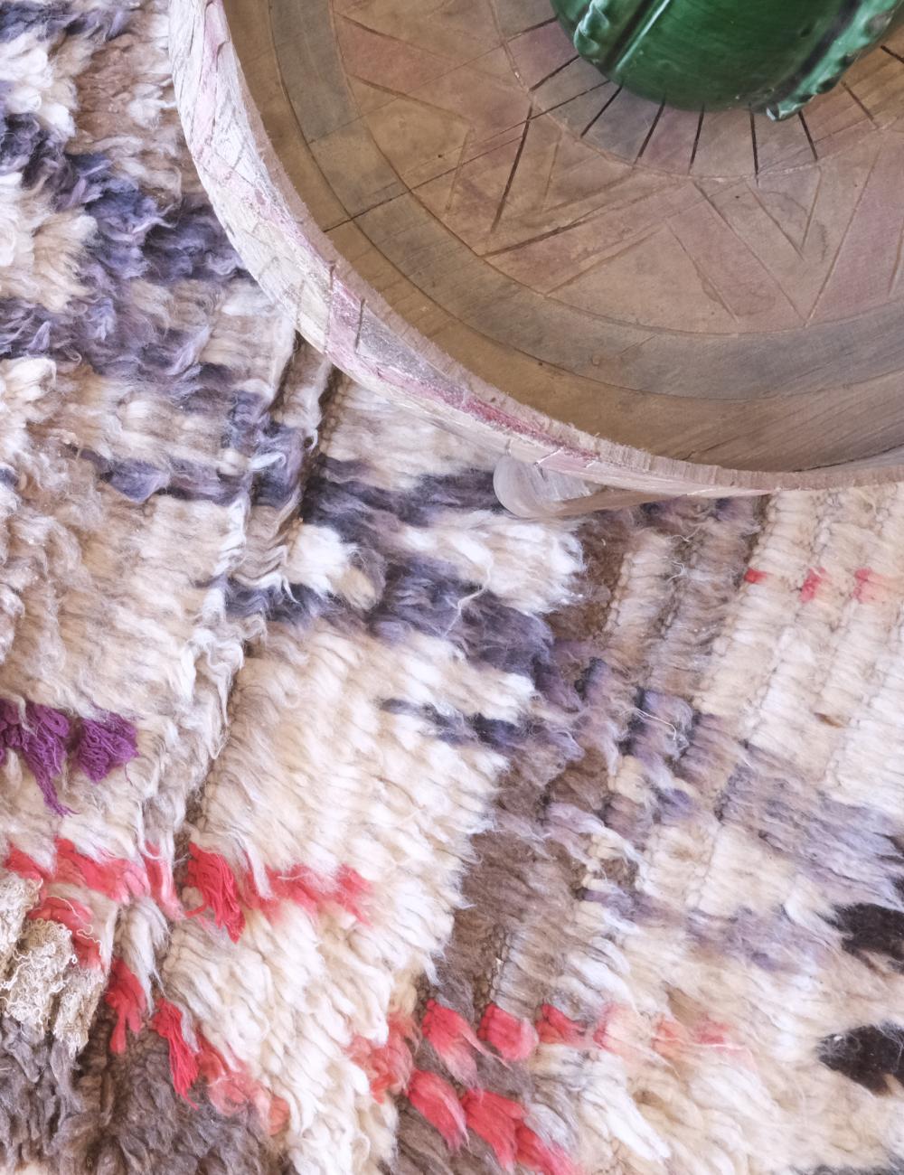 Close-up of a textured surface with a circular wooden object and colorful fabric.