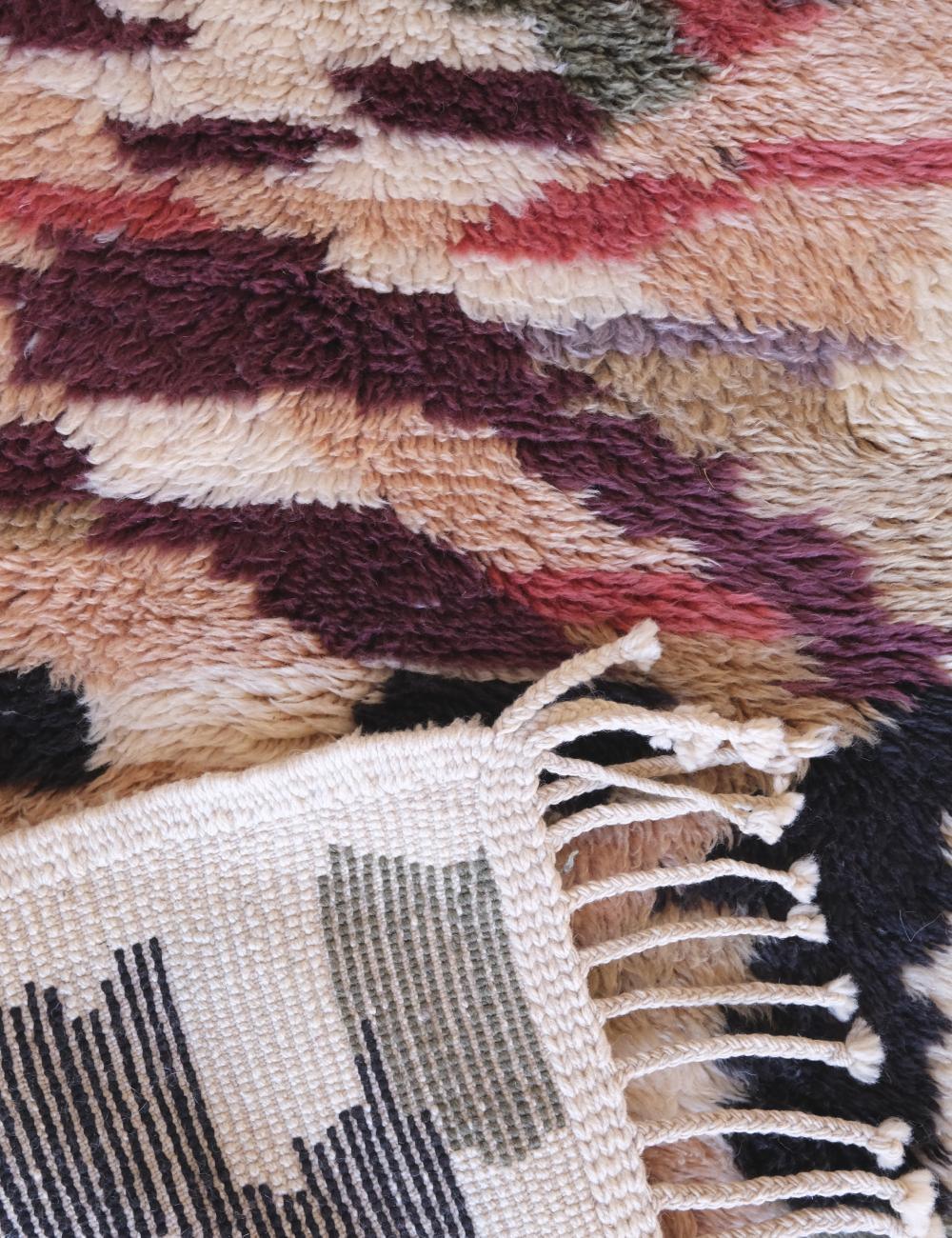 Close-up of a textured rug with geometric pattern and fringed edge.