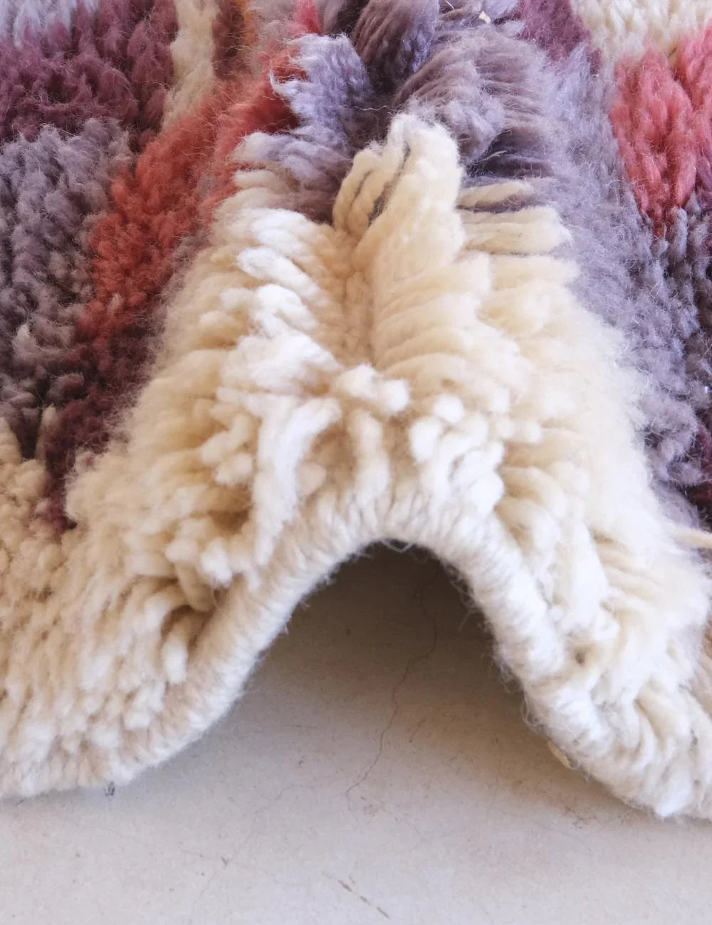 Close-up of a textured rug with a mix of colors on a light background