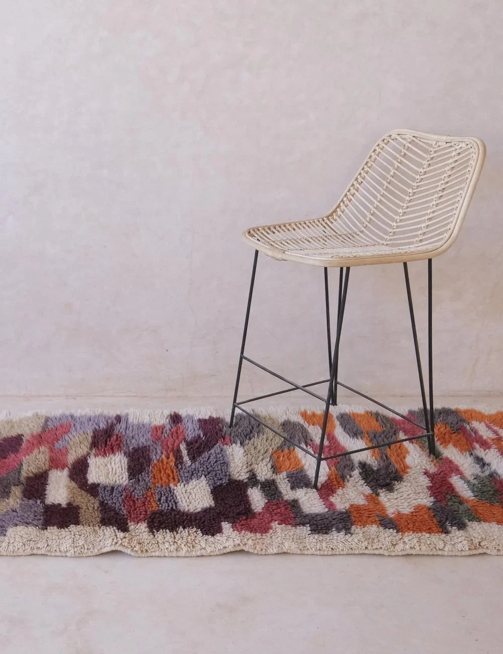 Multicolored geometric-patterned rug with a modern chair on a light background