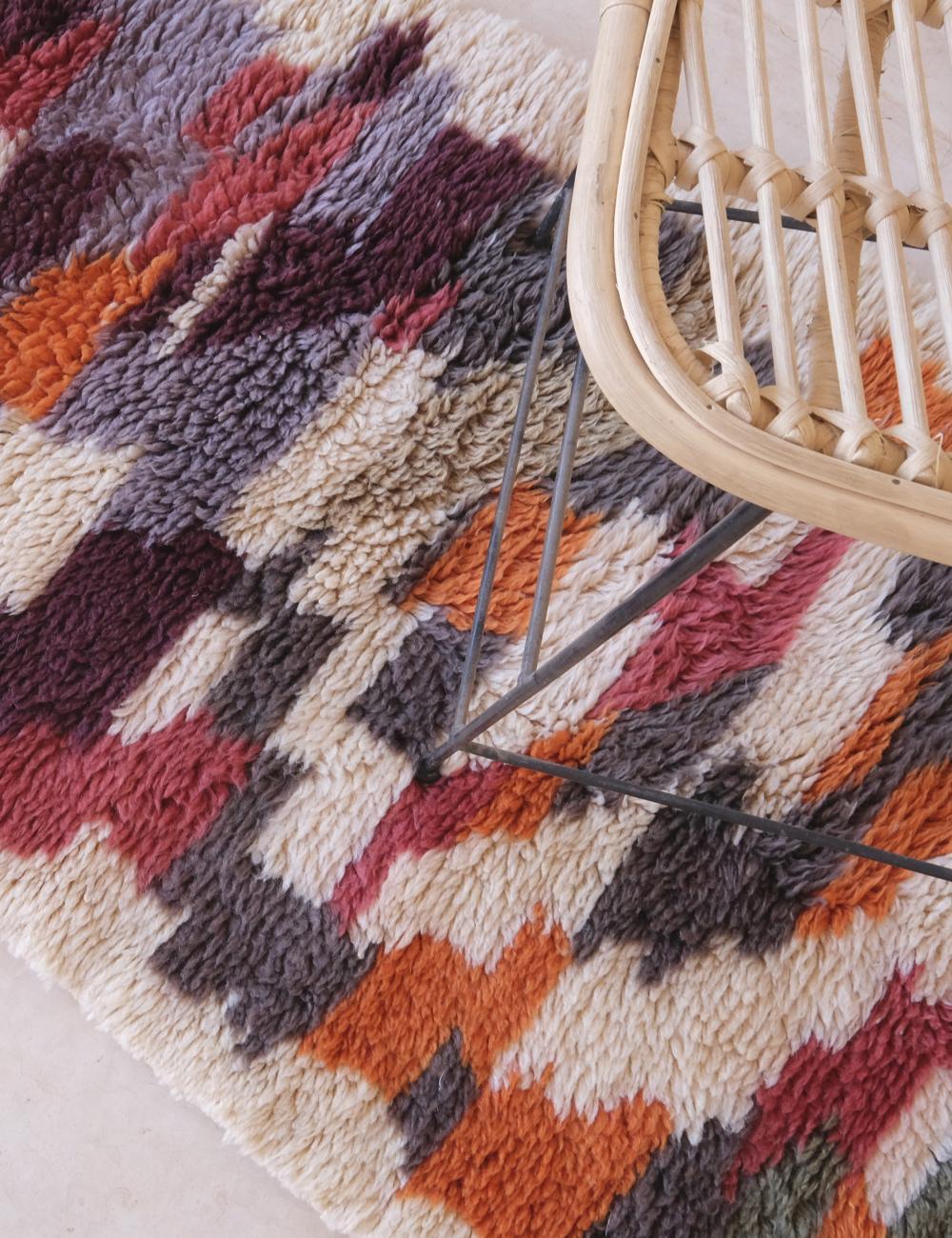 Multicolored geometric patterned rug with a wicker chair