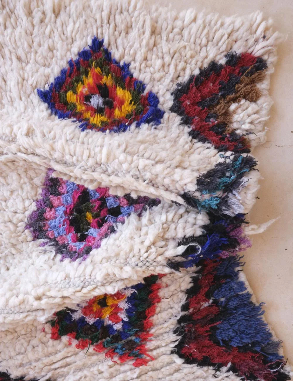 Textile art piece with colorful geometric patterns on a beige background