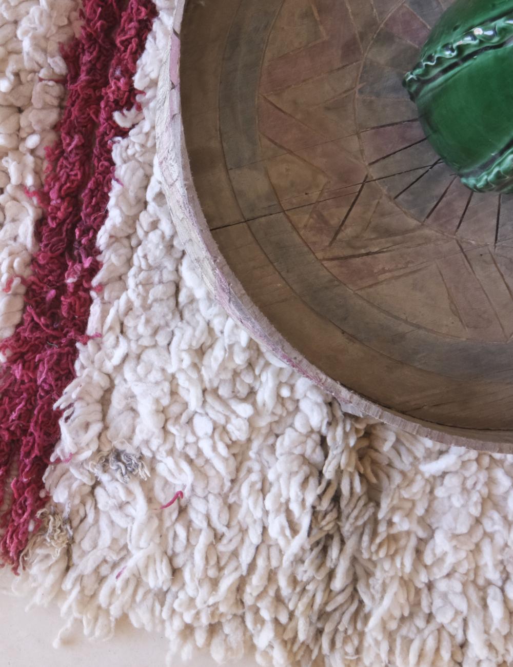 Close-up of textured fabric with a wooden bowl and green object in the background