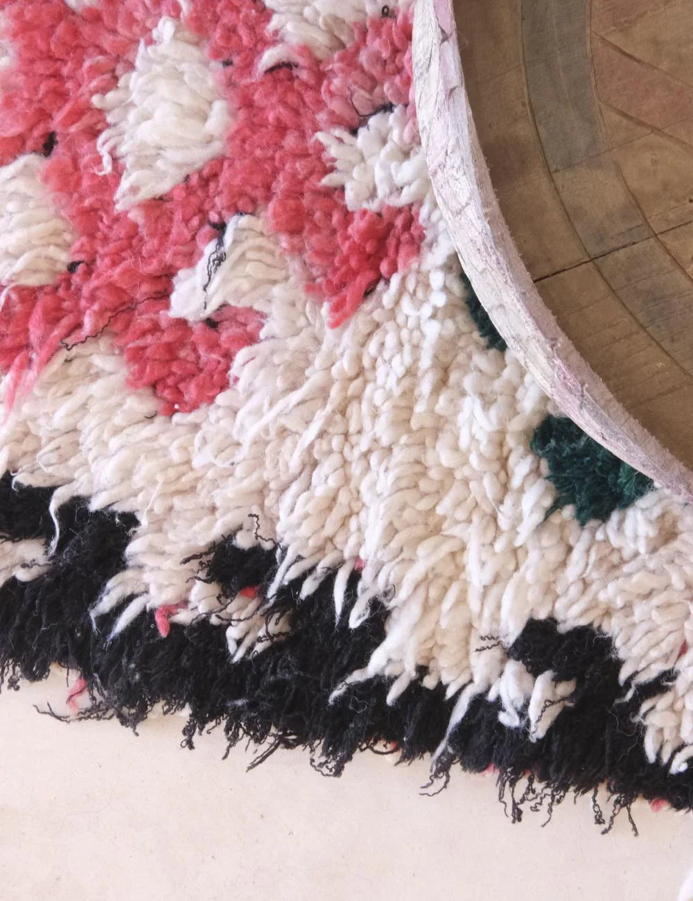 Close-up of a textured rug with pink, white, and black patterns.