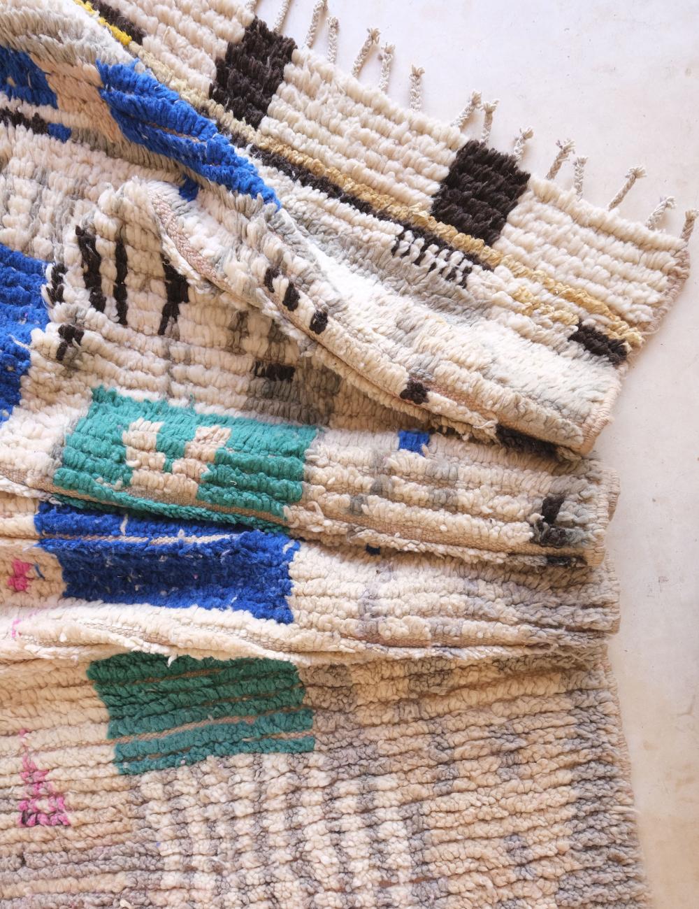 Stack of woven rugs with geometric patterns on a white background