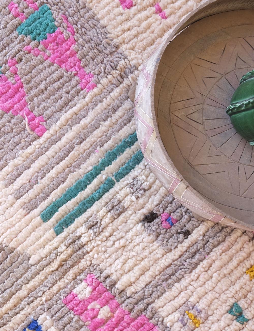 Close-up of a textured rug with geometric patterns and a decorative pot on top.